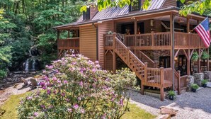 A cabin with a wooden exterior, a porch, and a staircase leading to an upper level. - KnightFall-Luxury Cabin w/Waterfall, Pet-Friendly (Maggie Valley)