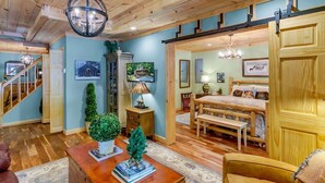A spacious living room with a wooden ceiling, a fireplace, a television, and a dining area with a bench and table. - KnightFall-Luxury Cabin w/Waterfall, Pet-Friendly (Maggie Valley)