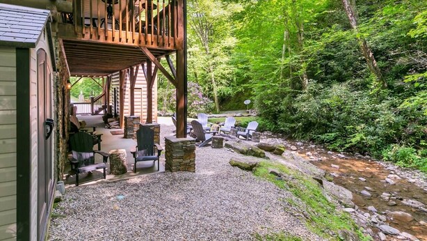 A cabin with a covered porch, outdoor seating, and a stream. - KnightFall-Luxury Cabin w/Waterfall, Pet-Friendly (Maggie Valley)