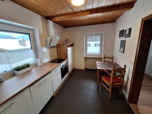 A compact kitchen with a wooden countertop, white cabinets, a built-in oven, and a dining area with a table and chairs.