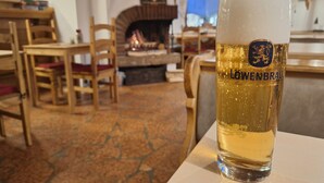 A glass of Löwenbräu beer in a cozy, rustic setting with wooden furniture and a fireplace. - Ferienwohnung mit Küche und Balkon (Reit im Winkl)