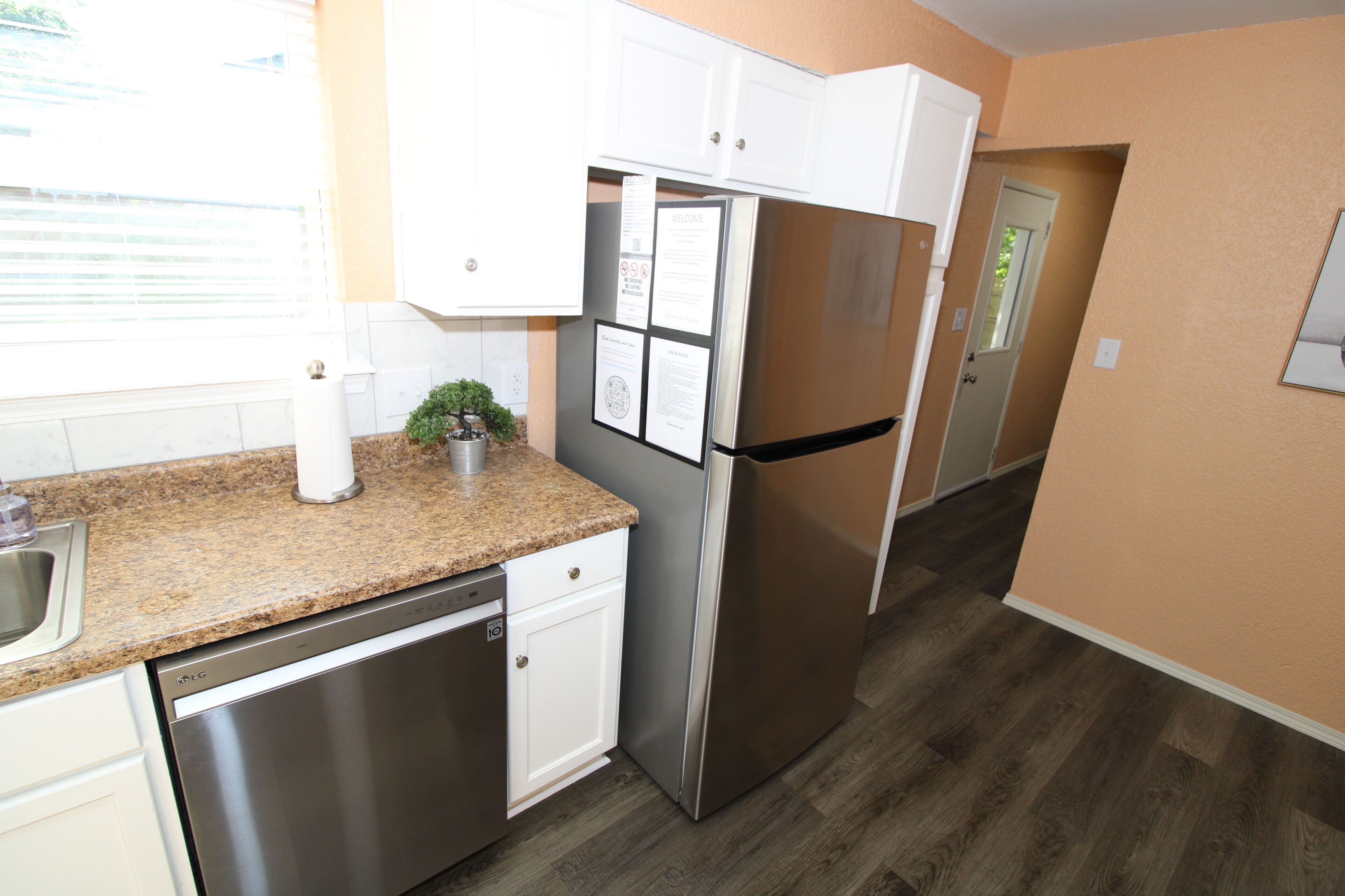A kitchen with stainless steel appliances, white cabinets, and a granite countertop.