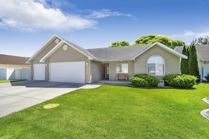 Stunning single-story home with a pitched roof and cozy porch area, set amidst a beautifully manicured lawn and mature trees.