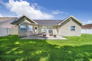 Stylish single-story home with a central entrance, flanked by windows, set amidst a well-manicured lawn and a fence.