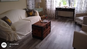 A living room with a sofa, a wooden chest, a lamp, and a desk with a computer. - Cozy Milbridge Country Home (Milbridge)