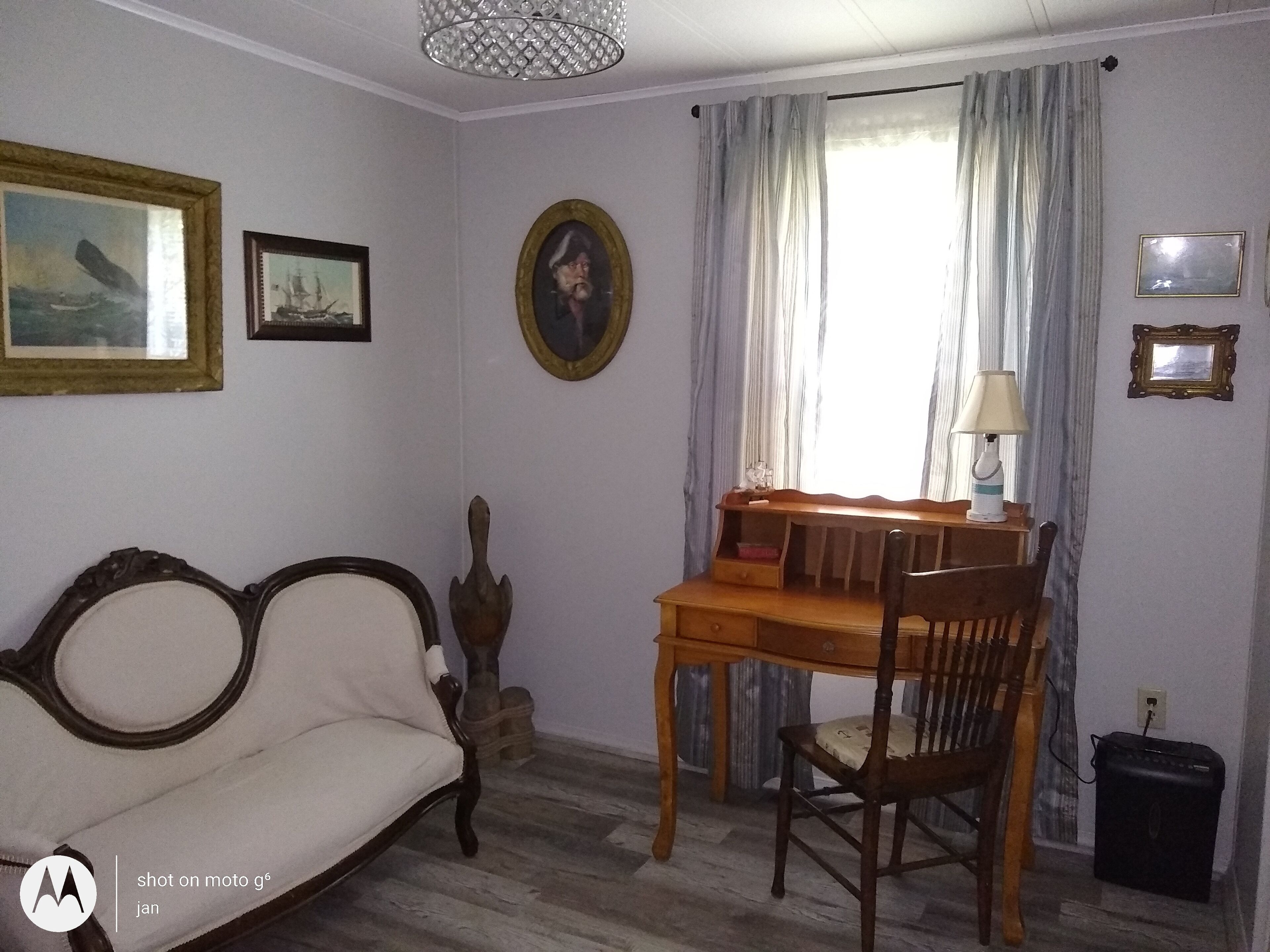 Ein Zimmer mit Holzschreibtisch, einem Sessel, einer Couch und einer Lampe.