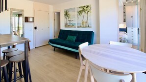 Un soggiorno moderno con un divano verde acqua, un tavolo da pranzo in legno e una sedia bianca.