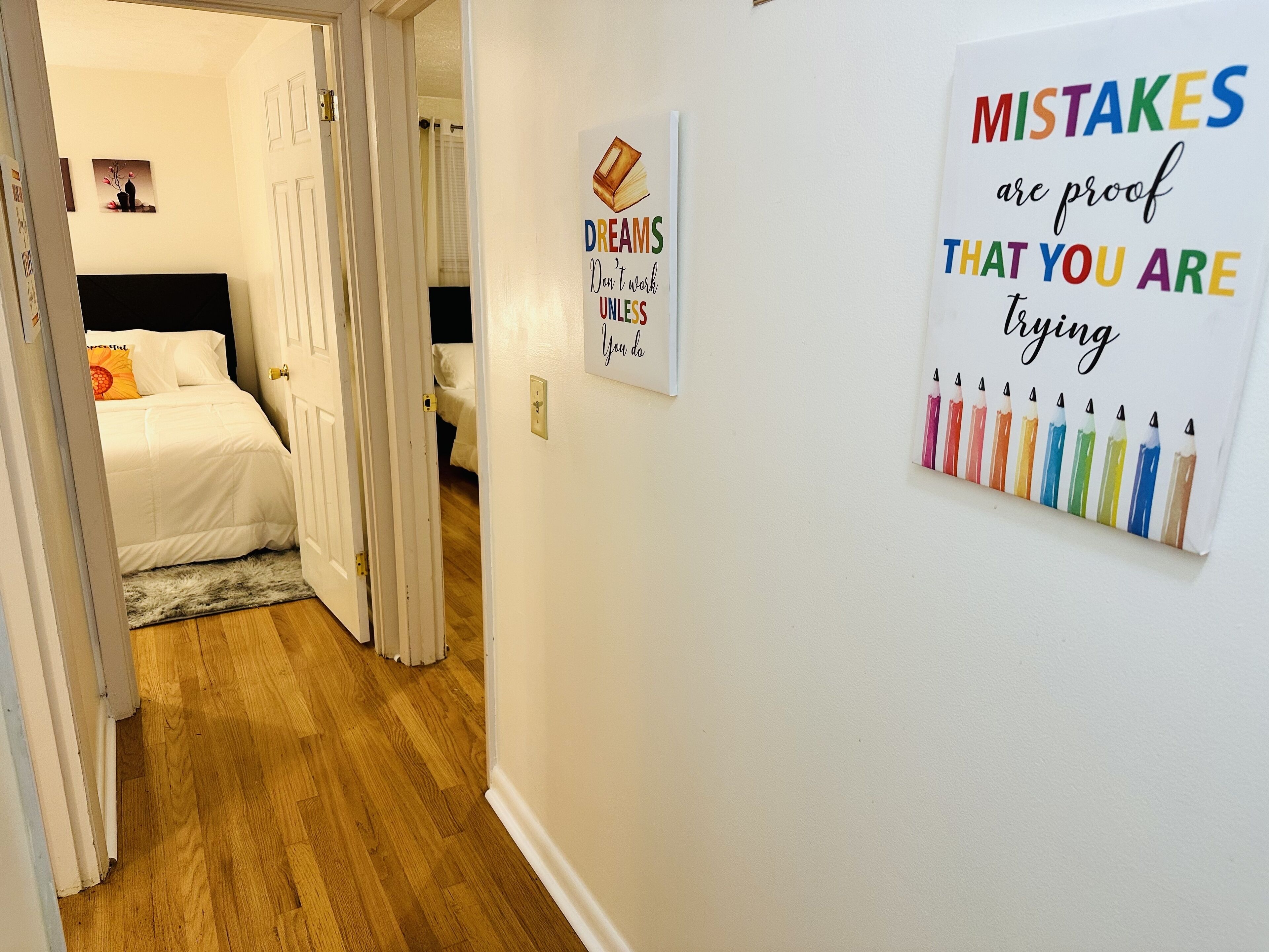 A hallway with a bed, a door, and motivational posters on the wall.