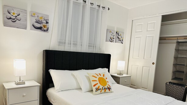 A neatly arranged bedroom with a bed, two bedside tables with lamps, a wardrobe, and artwork on the walls. - Sunshine Palace
Charming Tri-Level House with game room and large backyard! (West Chester)
