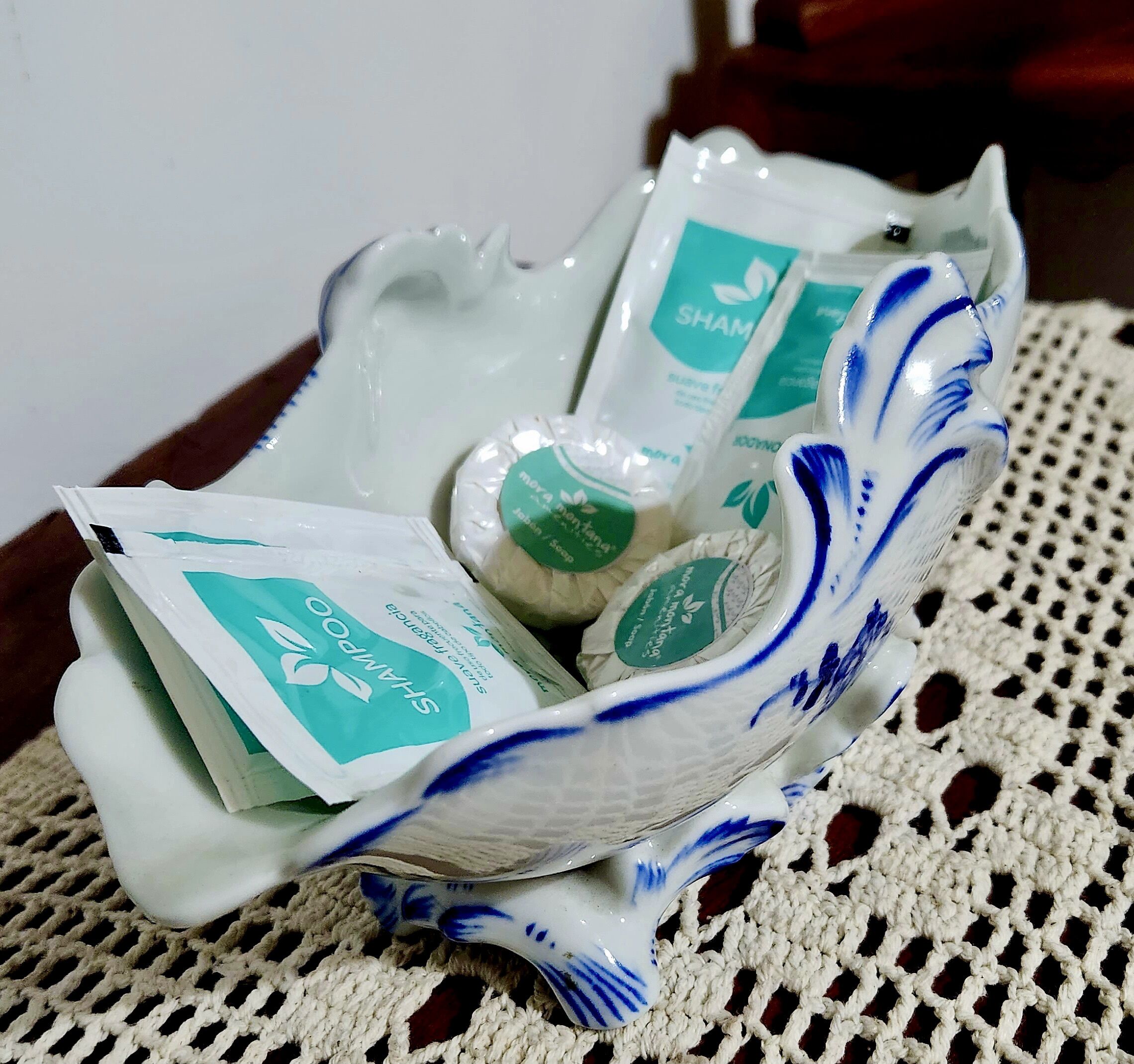 Uma tigela de cerâmica com padrões azuis contendo vários sachês de shampoo.
