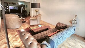 A modern living room with a large flat-screen TV, a sofa, a chair, and a coffee table.