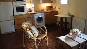 A compact kitchen with a washing machine, a microwave, and a dining area with a table and chair.