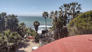 Blick auf die Küste mit Palmen, einem Strand und blauem Himmel.