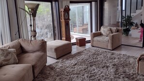 Ein geräumiges Wohnzimmer mit großem Fenster, einer Couch, einem Couchtisch und einer Topfpflanze.