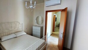 Een slaapkamer met een bed, nachtkastje, kaptafel, spiegel en een kroonluchter.