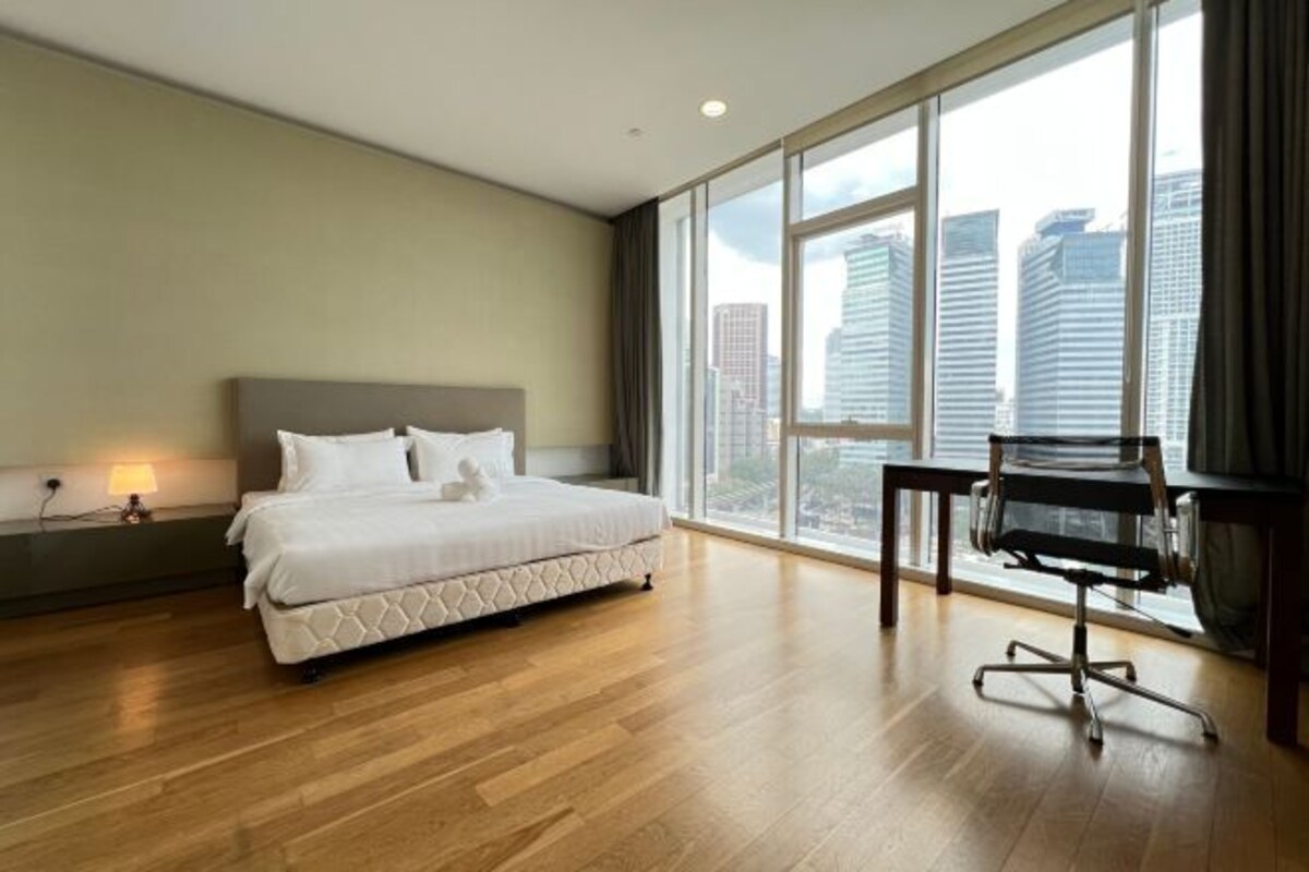 Una habitación de hotel moderna con una cama grande, un escritorio y vistas a edificios altos.