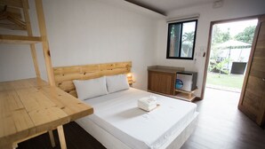 A bedroom with a wooden bed, a wooden table, a small cabinet, and a window overlooking a garden. - Hidden Lagoon Resort (Panglao)