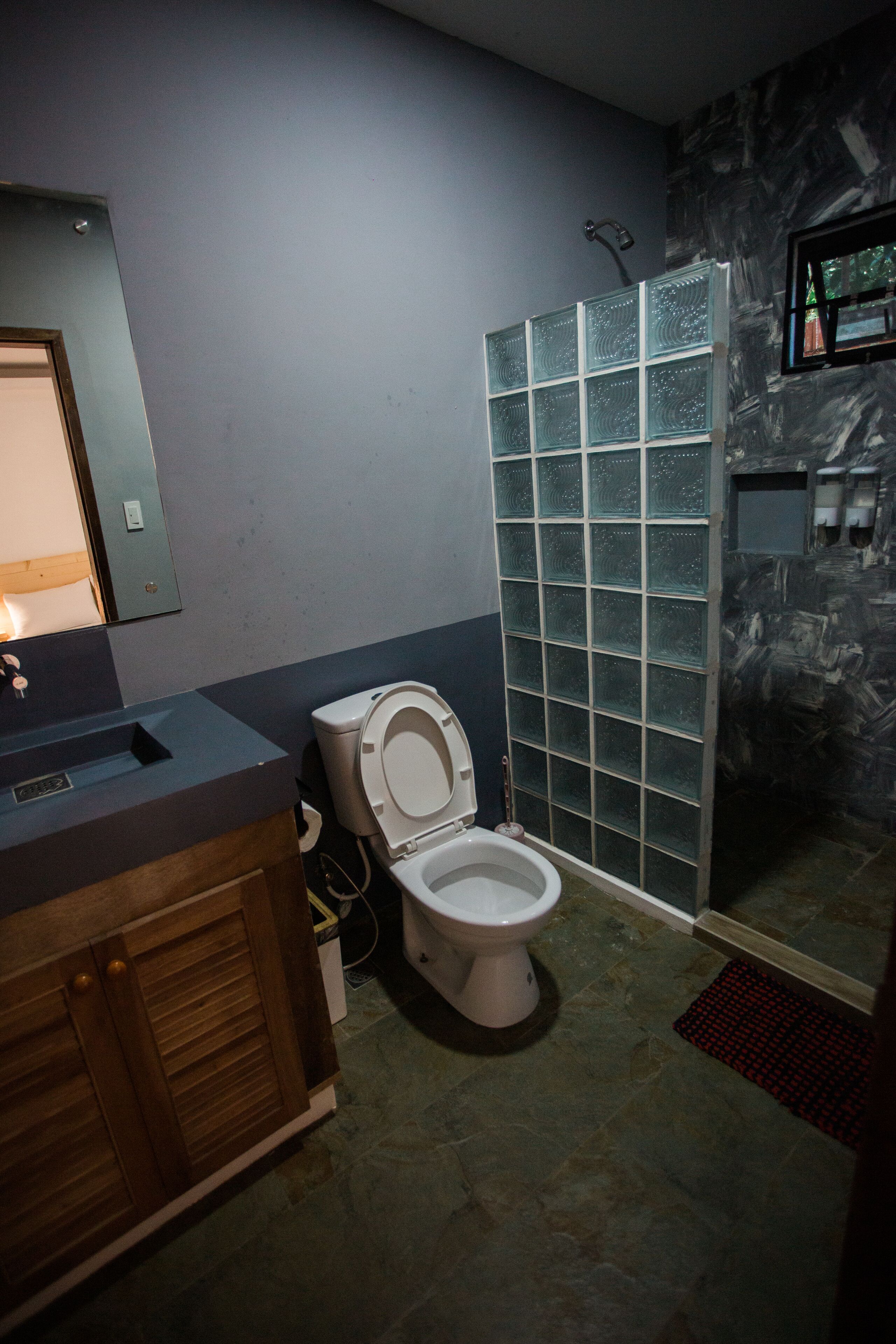 Une salle de bain équipée de toilettes, d’une douche et d’un meuble-lavabo en bois.