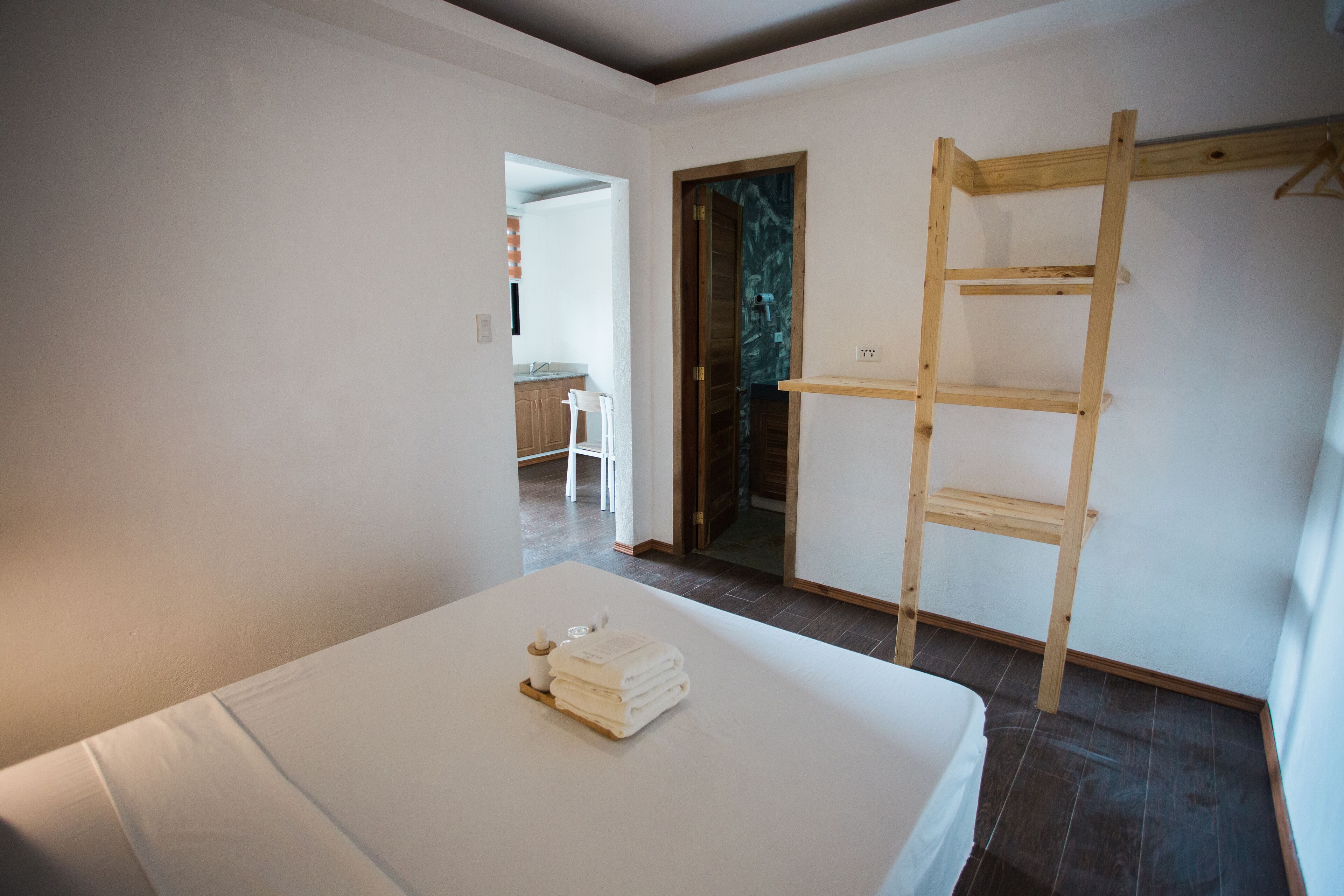 Una habitación con una cama, una escalera de madera y una puerta que da a otra habitación.