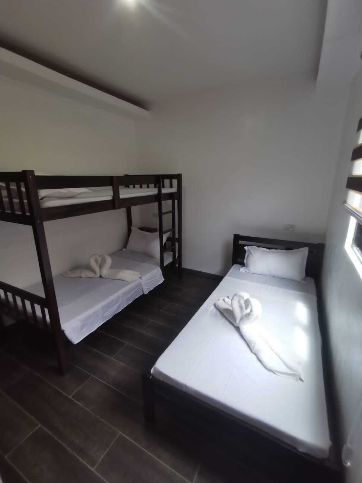 A room with two bunk beds and a single bed, all with white linens.