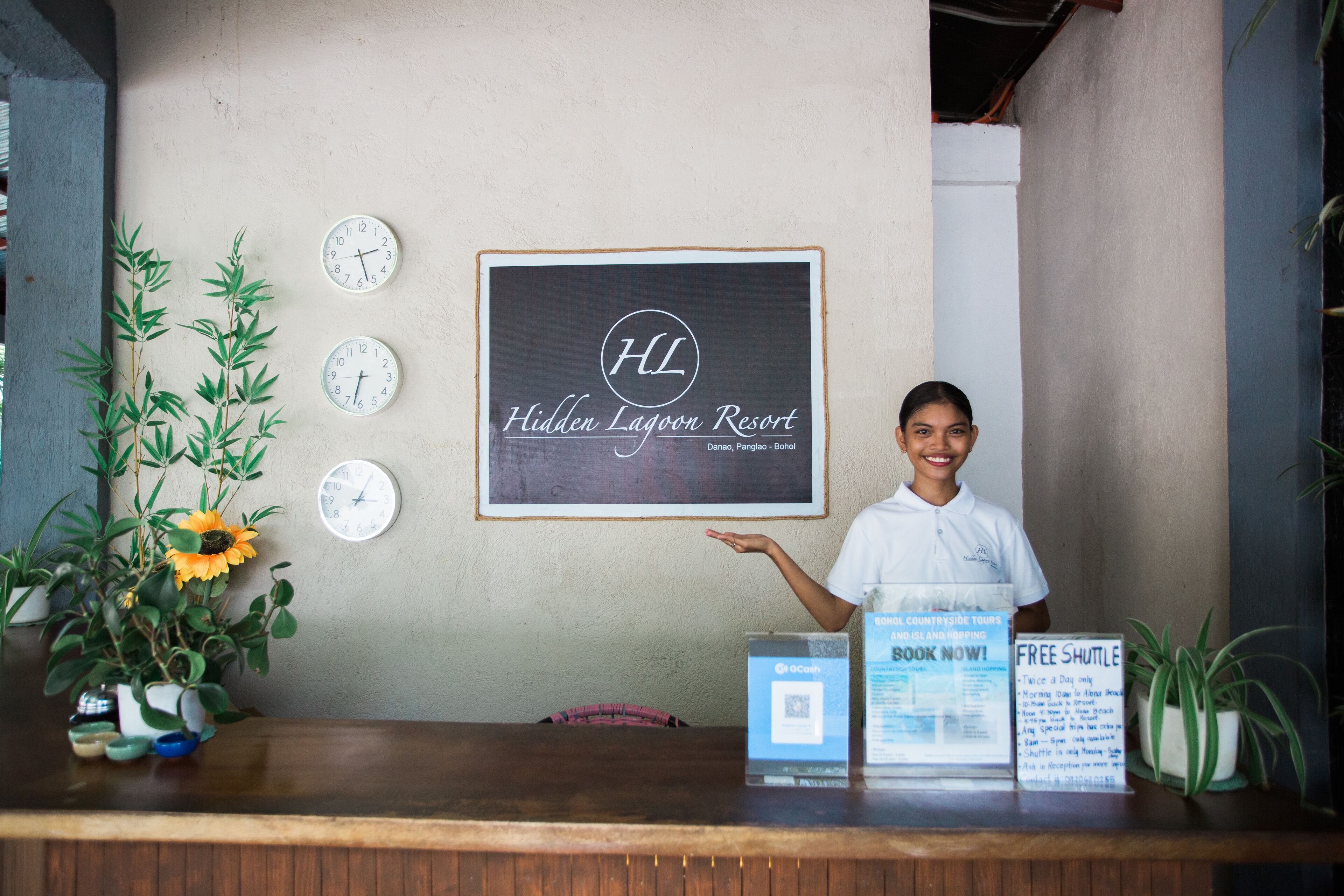 A reception desk at Hidden Lagoon Resort with clocks, a framed sign, and informational brochures.