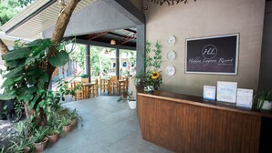 A reception area with a wooden counter, potted plants, and a sign for Hidden Lagoon Resort. - Hidden Lagoon Resort (Panglao)