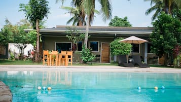 Una piscina al aire libre, sombrillas, sillones reclinables de piscina