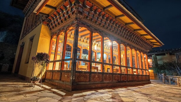 Un edificio tradicional con fachada de madera y ventanas grandes, iluminado durante la noche.