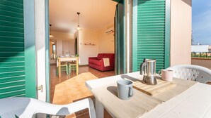 An open-plan living area with a dining table, a red sofa, and a kitchen visible through the open space.