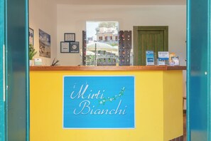 Un mostrador de recepción con un cartel que dice "Miti Bianchi" y varios carteles informativos y llaveros.