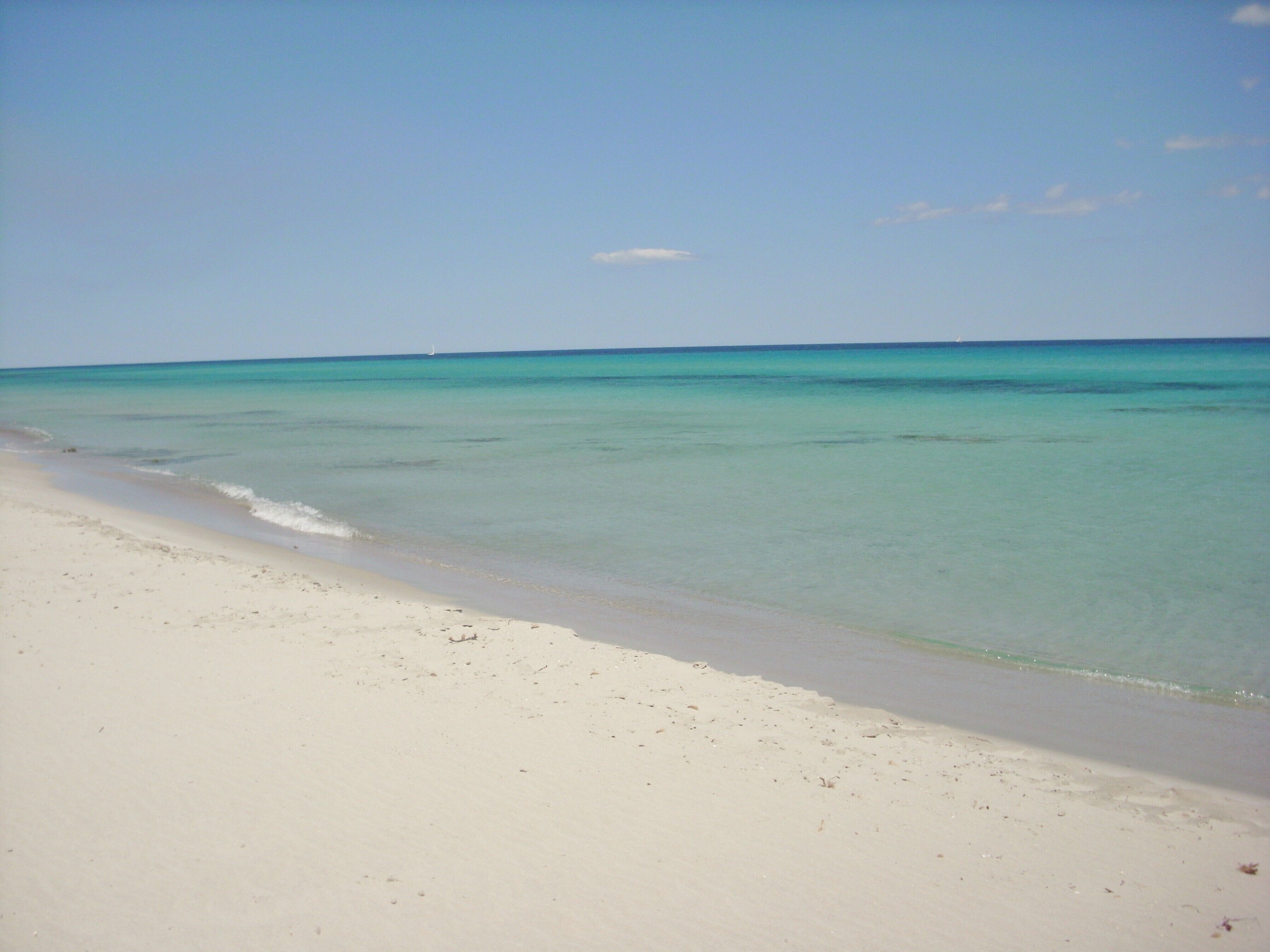 Ein Strand mit klarem türkisblauem Wasser und weißem Sand.