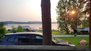 Uitzicht op een meer, met een auto op de voorgrond, een klein gebouw en een picknickplaats met een overdekte tafel.