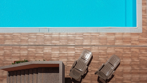 En pool med två solstolar och en stenmur.