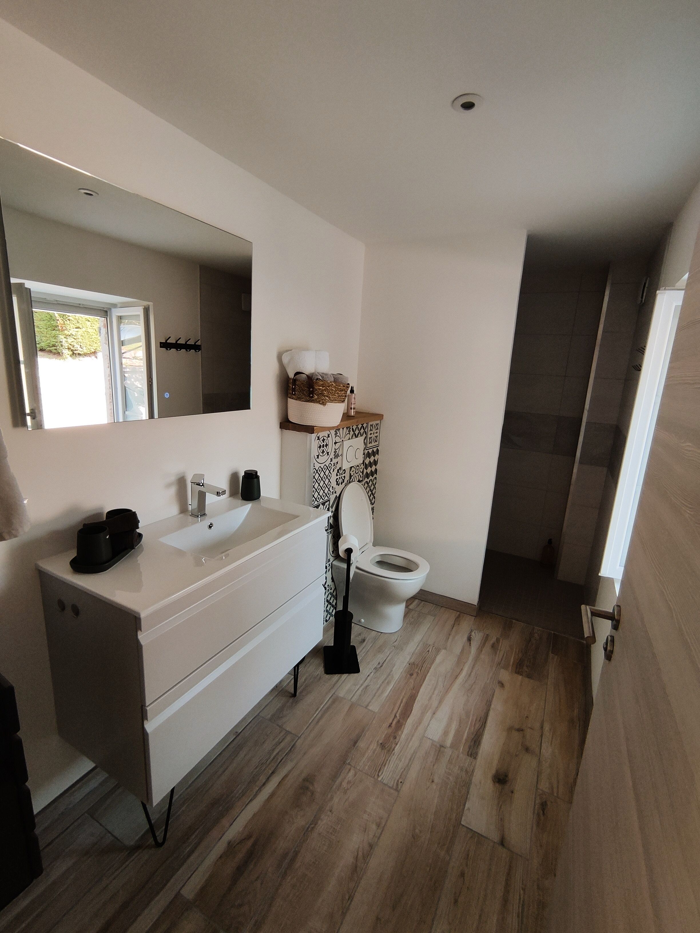 Une salle de bain moderne avec un meuble-lavabo blanc, deux vasques, des toilettes et un espace douche.