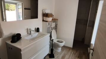 A modern bathroom with a white vanity, two sinks, a toilet, and a shower area.