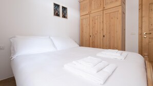 Un dormitorio con una cama grande, ropa de cama blanca y un armario de madera.
