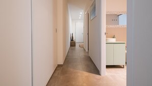 A narrow hallway with a tiled floor leading to a room with a sink and cabinets. - La Casa di Guido in Gabicce Mare (Gabicce Mare)