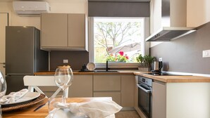 A modern kitchen with a dining area, featuring a built-in oven, a window with a view of the outdoors, and a dining table set with plates and a wine glass. - La Casa di Guido in Gabicce Mare (Gabicce Mare)