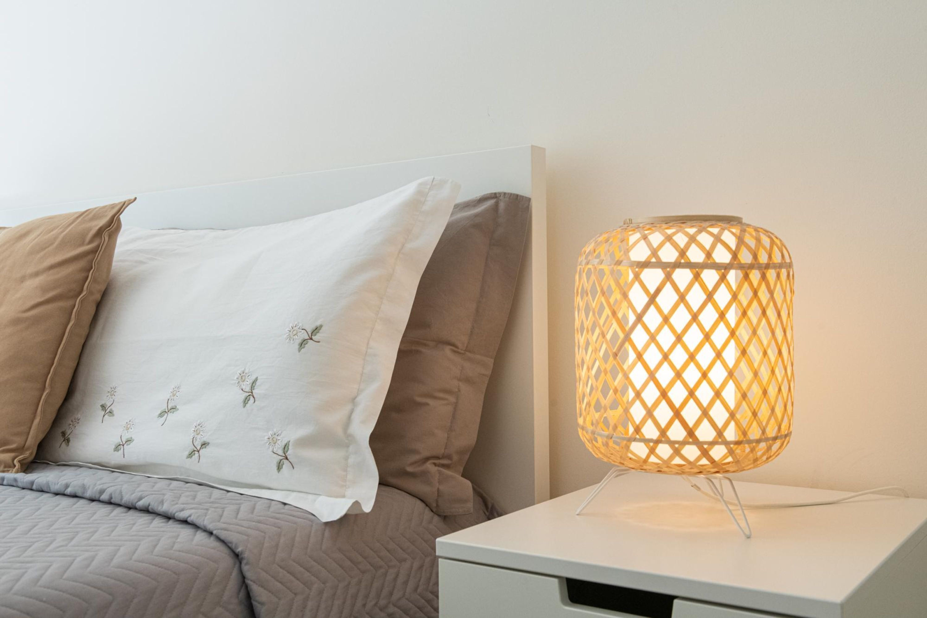 A bed with pillows and a bedside table with a lamp.