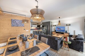 Un espacio habitable moderno con comedor, asientos, cocina y televisor.