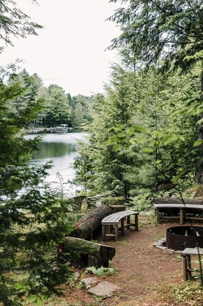 A lakeside campsite with wooden benches and a fire pit.