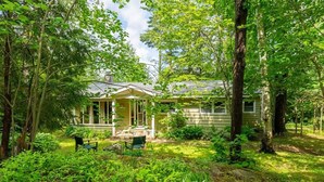 A house surrounded by lush greenery, with a porch and a small garden area.