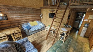 Een gezellig cabin interieur met een hoogslaper, een bank, een eettafel en een ladder.