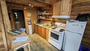 Een kleine keuken met houten kastjes, een kookplaat, een koelkast en een spoelbak.
