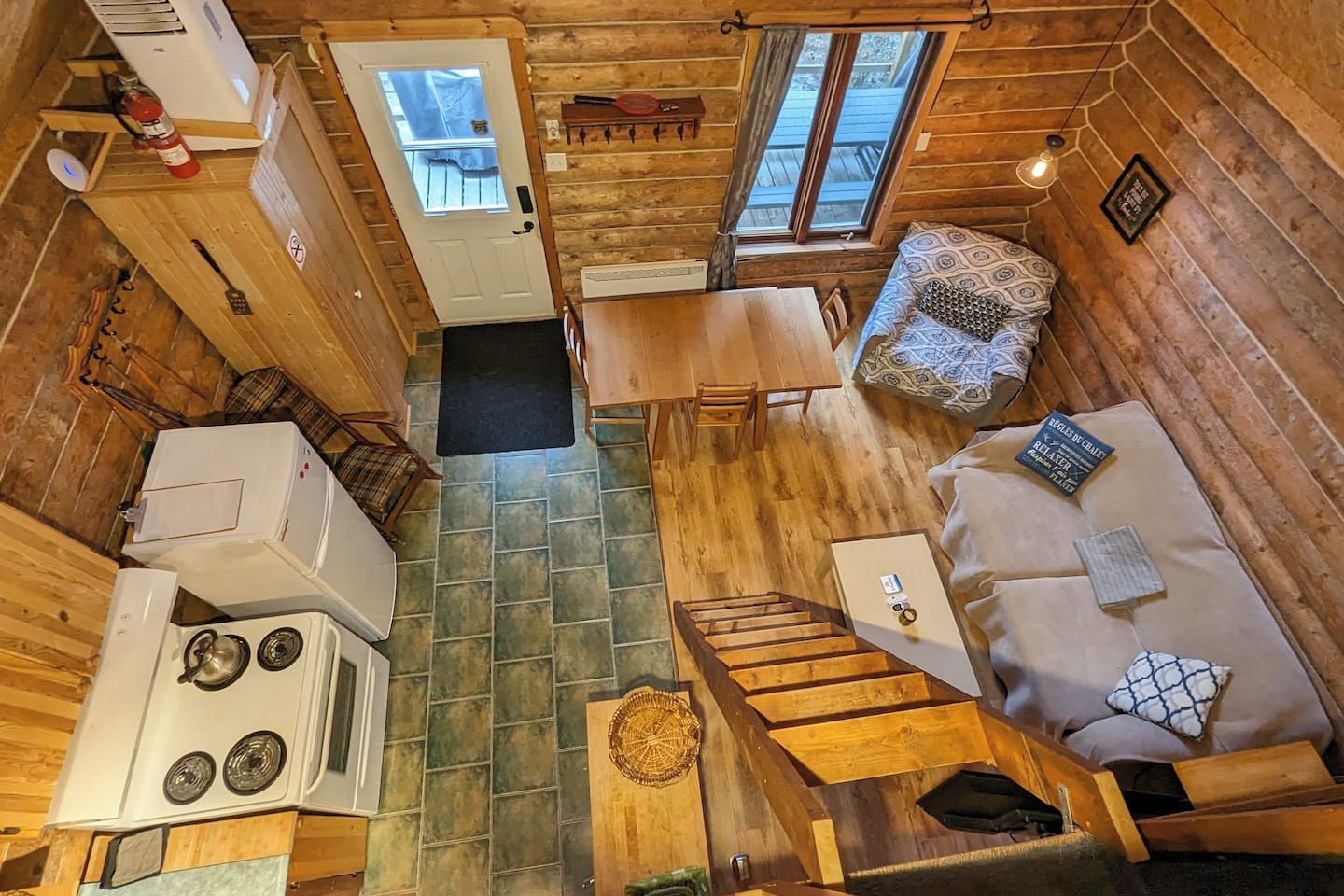 A compact cabin with a kitchenette, a dining area, and a seating area with a sofa and a patterned cushion.