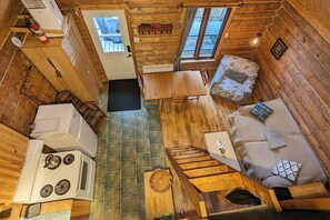 Une petite cabine comprenant un coin cuisine, un espace repas et un coin salon avec un canapé et un coussin à motifs.