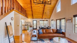 A spacious living area with a wooden ceiling, a brown leather sofa, a coffee table, and a colorful rug. - Valley Retreat! Sleeps 10 ~ Hot Tub ~ Fire Pit (Blue Ridge)