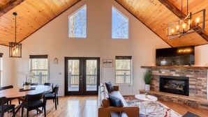 A spacious living area with a high ceiling, a fireplace, and a large window. - Valley Retreat! Sleeps 10 ~ Hot Tub ~ Fire Pit (Blue Ridge)