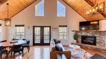 A spacious living area with a high ceiling, a fireplace, and a large window.
