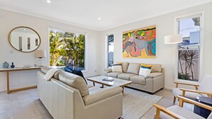 A modern living room with a sofa, a coffee table, and a painting on the wall. - The Art House @ Beachside (Yaroomba)